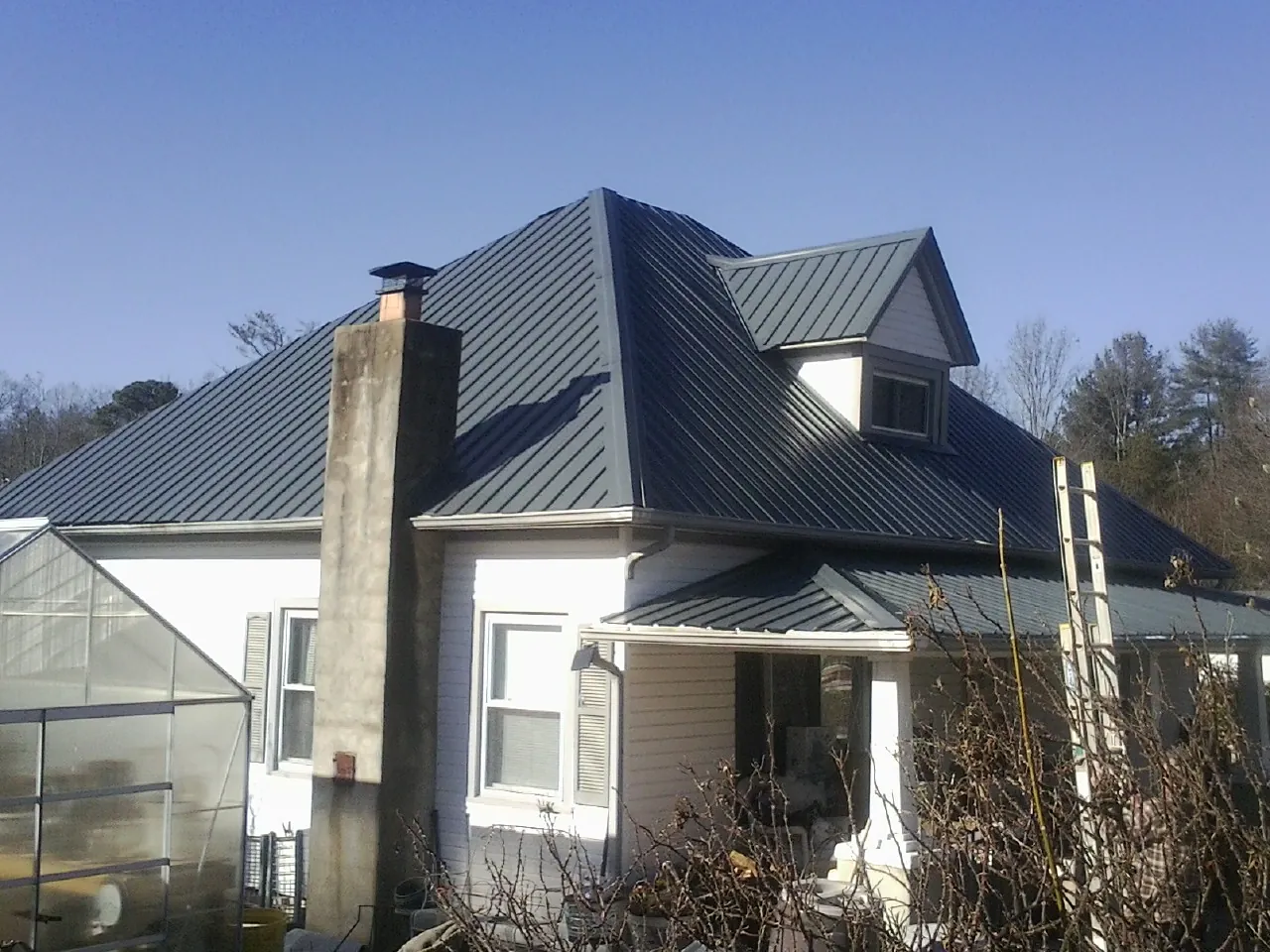 Dark blue standing seam metal roof on a white farmhouse with dormer — Slate & Tile Roof Repair by Roofing Brothers in Olympia Fields