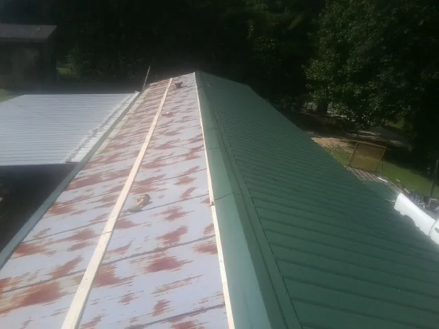 Old rusted panels beside newly installed green metal roofing — Wind Damage Roof Repair by Roofing Brothers in Olympia Fields