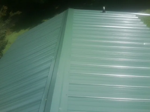 New green metal panels meeting at the ridge of a roof — Flat Roof Repair work by our crew in Olympia Fields