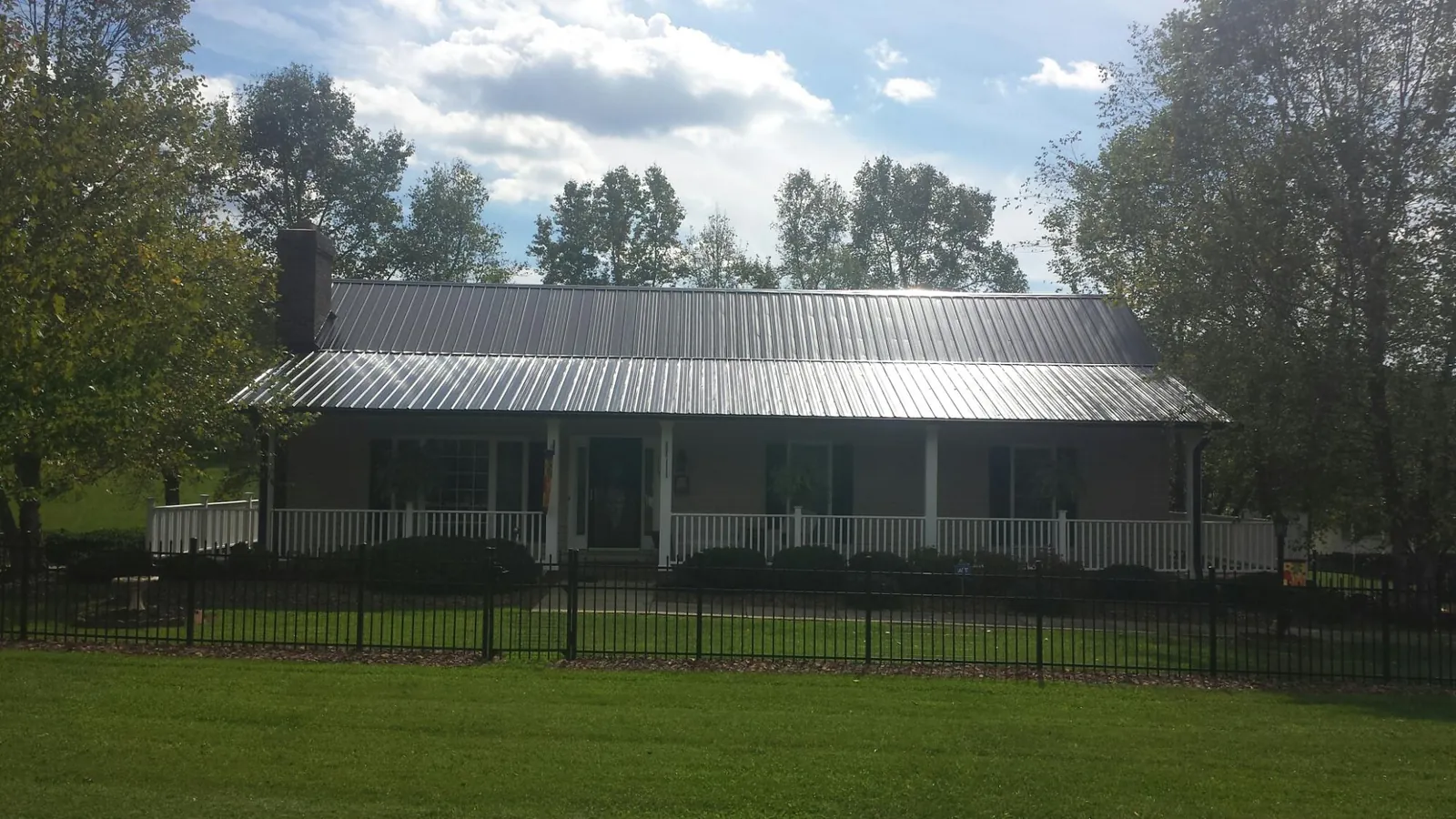 Gray metal roof on a brick ranch with a full width front porch — Gutter Guard Installation work by our crew in Olympia Fields