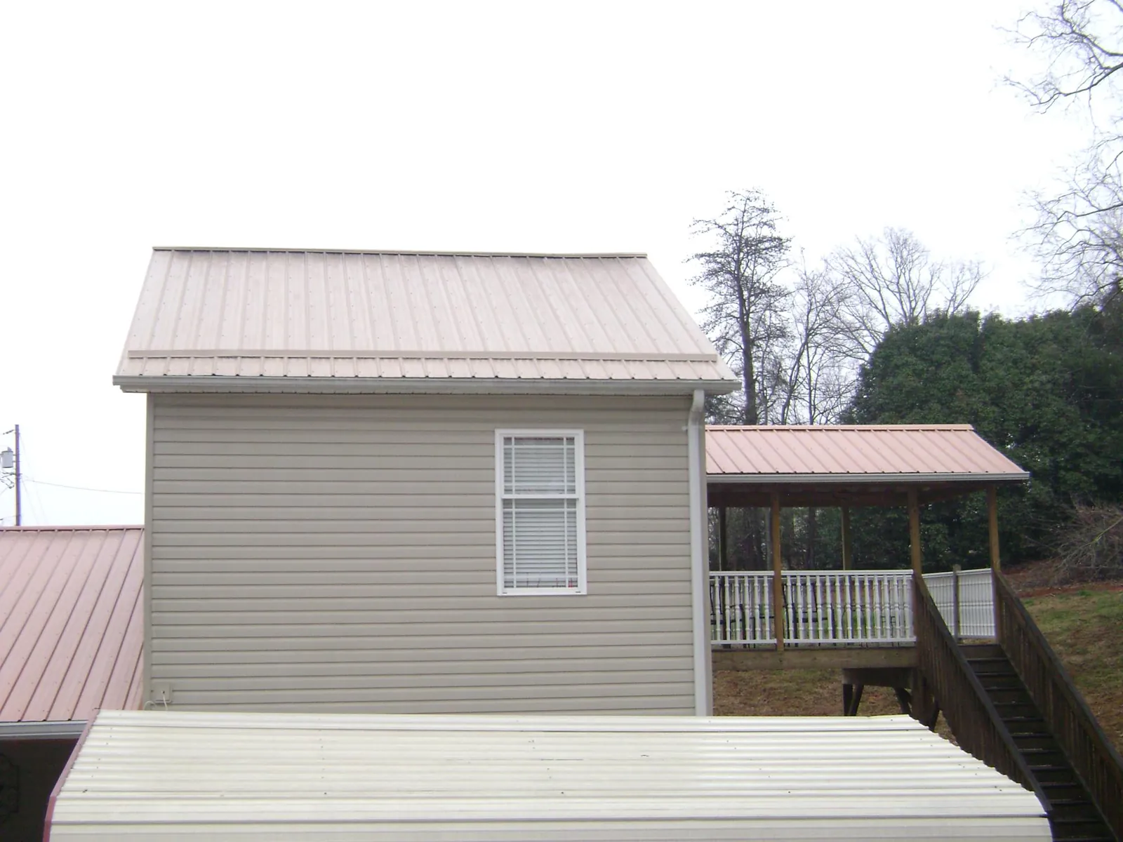Tan metal roofs on a two story addition and attached porch, from a Roof Replacement job in Olympia Fields