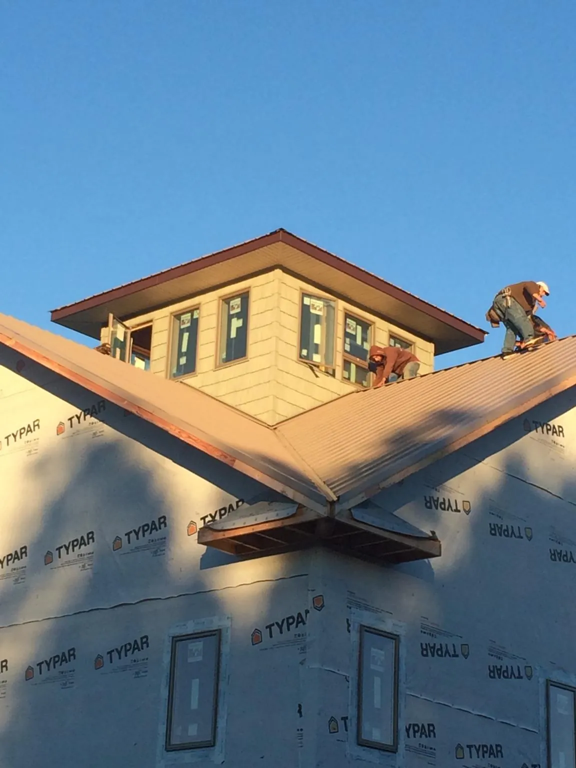 Roofers working around a rooftop cupola on a new metal roof at sunset — Roof Waterproofing in Olympia Fields by Roofing Brothers